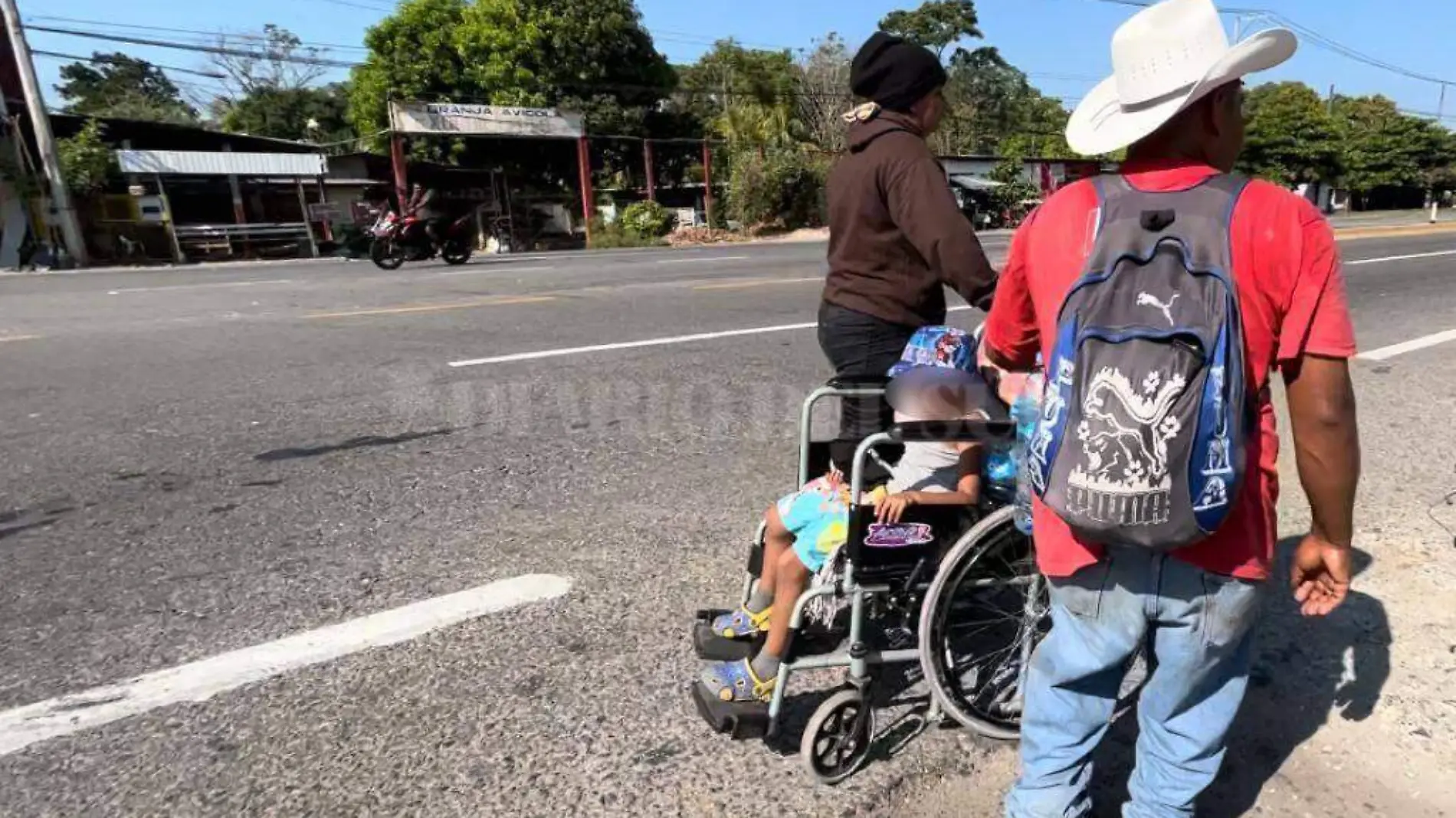 niño migrante en silla de ruedas acompañado por su familia